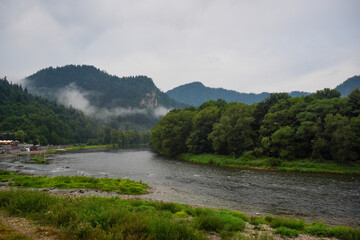 Fototapeta na wymiar Panorama of the river and mountain view at dawn, fog over the water on a cloudy day. Landscape in Szczawnica, Poland. Beskidy mountains, three crowns trzy korony mountain, Dunajec river