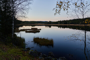 Fototapeta na wymiar Triungsvanna, Oslomarka, Norway. Nature reserve. Shot in golden/blue hour in october. A crisp and cold evening in Nordmarka. This lake and forest is only a few kilometers from down town city of oslo.