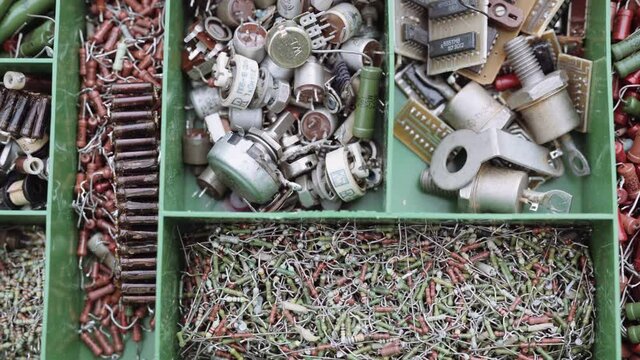 A box with a variety of radio components. A scattering of various old radio parts transistor resistor diode.