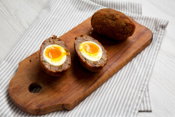 Homemade Scotch Eggs on a rustic wooden board, side view.