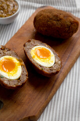 Homemade Scotch Eggs on a rustic wooden board, side view. Close-up.