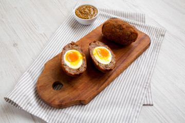 Homemade Scotch Eggs on a rustic wooden board, low angle view.