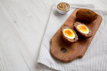 Homemade Scotch Eggs on a rustic wooden board, side view. Copy space.