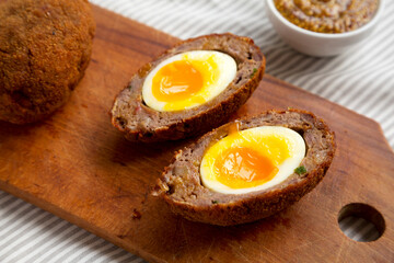 Homemade Scotch Eggs on a rustic wooden board, side view. Close-up.
