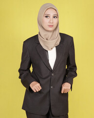 Hijab female models pose like famous models. The woman is wearing a set of office suits. pose while standing and sitting on a tall wooden chair.