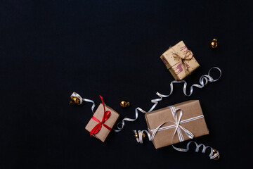 Obraz premium gifts for Christmas, wrapped in wrapping paper and tied with a ribbon, next to the Golden Christmas balls are on a black background. The view from the top. Flatley