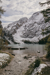 Wooden rowing boats on Braies lake in Dolomites during autumn or winter season. Emerald water, green pine trees with snow in the top of mountains. Desolate, wild, low-season concept.