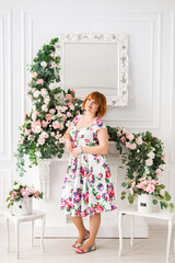 cheerful woman in a dress with flowers stands on a background of flowers