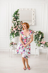 cheerful woman in a dress with flowers stands on a background of flowers