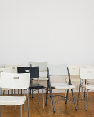 black chair in the group of white chairs in a neutral studio space