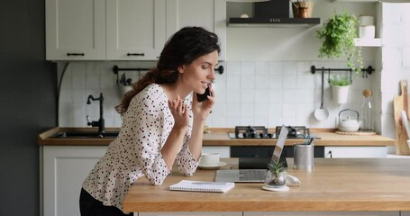 Woman standing in kitchen hold smartphone talking with workmate solve issues distantly due quarantine self-isolation. Client make order from home by phonecall. Informal chat using modern tech concept
