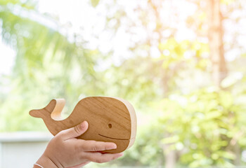 Wooden whale toy in children's hands. The concept of love of the environment and ecology. Copy...