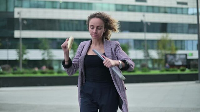 A young woman, an office worker, is in a hurry on business and has a snack on the way.