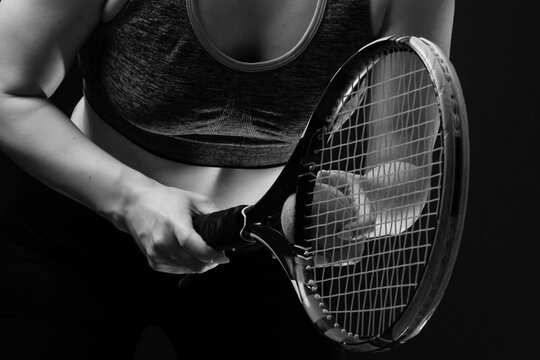 Female tennis player with racket and ball on black background