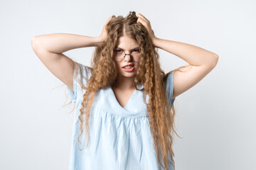 Obraz premium Embarrassed young pretty girl holding her head looking at camera. Studio shot, white background. Human emotions concept