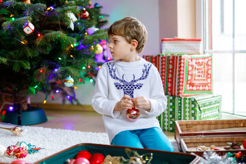 Beautiful kid boy and colorful vintage xmas toys and balls. Child decorating Christmas tree