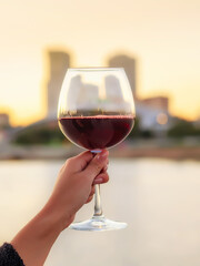 womans han holding glass of wine  on the background of the night city. Panoramic restaurant. cocktail on the background of skyscrapers. Wineglass overlooking the evening city. Romantic atmosphere