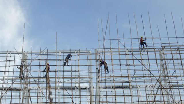 Hong Kong construction worker erecting bamboo scaffolding on top of a tall building in Hong Kong.
