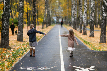 Fototapeta premium children girls friends walk in the park wearing masks, without touching, children walk keeping a distance, protection from the virus, social distance and friendship, quarantine and restrictions