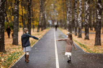 Fototapeta premium children girls friends walk in the park wearing masks, without touching, children walk keeping a distance, protection from the virus, social distance and friendship, quarantine and restrictions