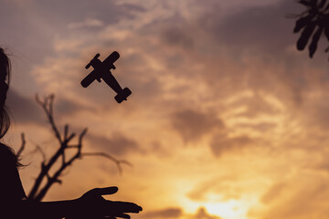 Silhouette of hand holding airplane in nature at sunset. The pilot is that dream in the future of the boy. Copy space.