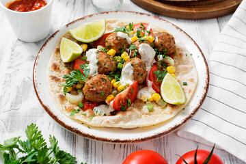Tortilla with grilled meatball, corn and fresh salad.	