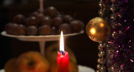 Burning Christmas candle on the background of tinsel and toys