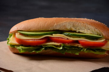 Sandwiches with cheese, lettuce, tomatoes and onion on a on a dark background
