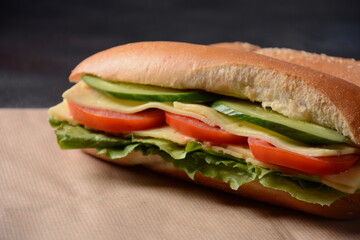 Sandwiches with cheese, lettuce, tomatoes and cucumber on a on a dark background