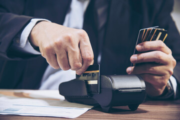 Business man holding many credit cards and trying to use credit card machine