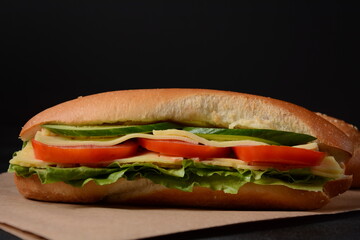 Sandwiches with cheese, lettuce, tomatoes and cucumber on a on a dark background