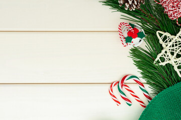 Christmas or New year composition on white wooden background. Natural pine branches, jingle bell, candy cane as Xmas design. Top view with copy space.