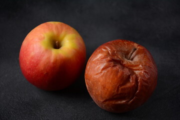 Rotten wrinkled skin apple and fresh apple on black background. Ugly food concept