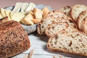 Sliced rustic bread and cheese on a white wooden board. Healthy food and farming concept