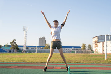 Fototapeta na wymiar Teenager girl working out at the stadium doing jumping jacks