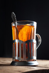  tea with lemon in a glass with a cup holder on a wooden background with a black background