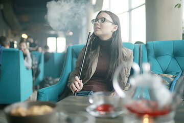 adult girl smokes a hookah in a cafe / modern interior, smoking, smoke, night club, day.