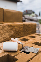 Fototapeta na wymiar Mason tools in the workplace - a trowel and a mallet lie on a concrete block wall under construction