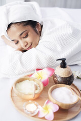 Obraz na płótnie Canvas Smiling Asian woman in white headscarf and bath towel lie down and relaxing on bed preparing for massage therapy at alternative medicine healing spa Center in Th