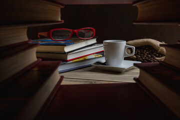 Taza de café junto a algunos libros de tapa dura