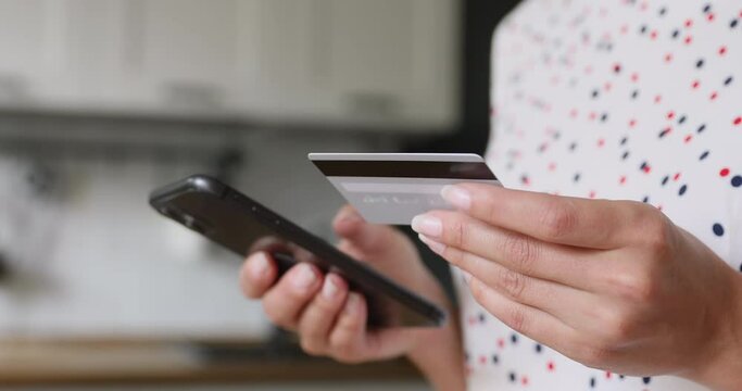 Close up view unrecognizable female hands holding credit card and smartphone enter numbers purchasing on internet websites. Send money to family easy instant finance transfer application usage concept