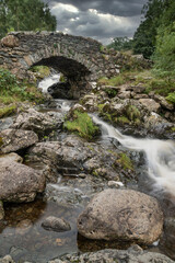 Stunning long exposure landscape image of Ashness Bridge in English Lake District during late Summer afternoon with dramatic lighting