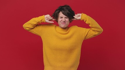 Sad displeased young woman 20s years old in yellow sweater posing isolated on red wall background in studio. People emotions lifestyle concept. Closed eyes cover ears do not want to listen screaming