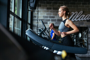 Obraz na płótnie Canvas Young fitness girl running on treadmill machine.