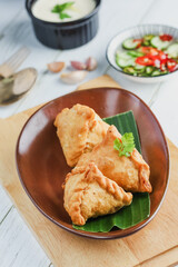 Samosa on a plate with sauce. Indian fried pastry with a savoury filling as spiced, potatoes, onions. Savory desserts. Spicy snack. A common street snack in Northern India