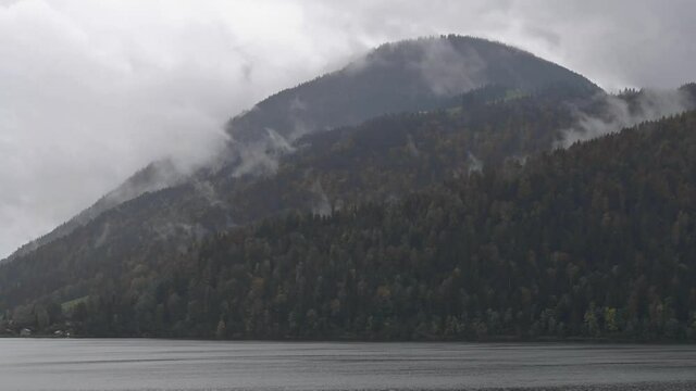 Time-lapse  shot of heavy autumn rain, fog and clouds formation, and turbulent cloudy sky over Aegeri lake and Rossberg mountain covered with virgin H&ouml;lliwald forest, Pre-Alps, Central Switzerland