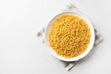 Raw ditalini pasta in white plate on white. View from above.