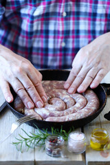 The chef puts raw sausages in a skillet. Cooking Bavarian sausages. Selective focus.