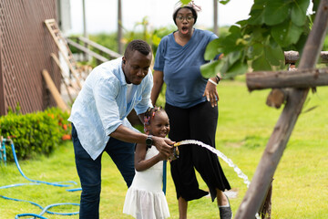 African American cute girl water the plants outdoors at home.