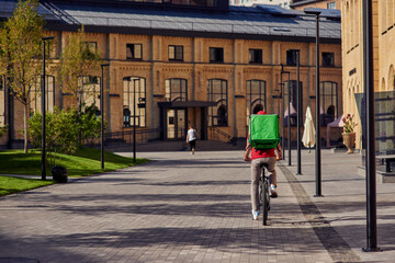 Courier on bicycle riding along beautiful sunny street